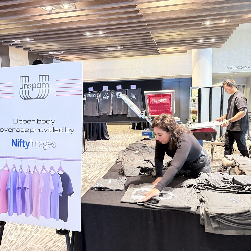 Crew member folding finished garments on a long table inside a hotel ballroom