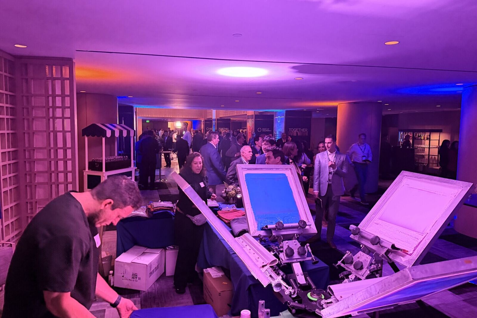 Evening event space in violet light with guests gathered near the station